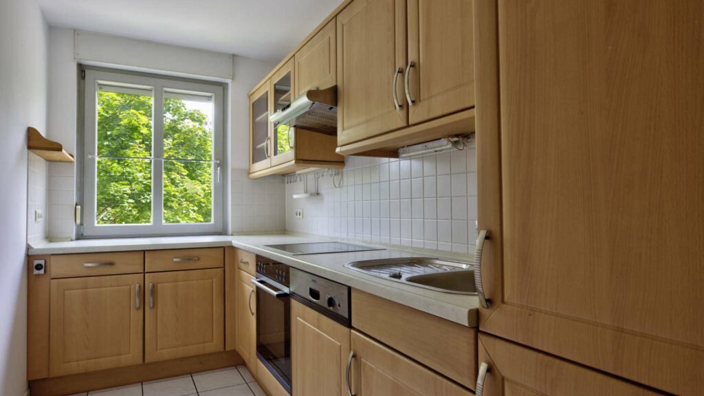 Küche der Wohnung in Berg am Laim mit Holzfronten, Fenster, Spüle und Einbauherd