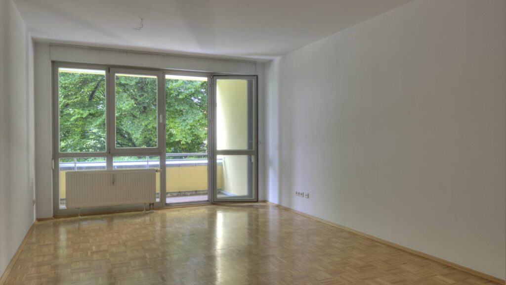 Leeres Wohnzimmer der Wohnung in Berg am Laim mit Parkettboden und großer Balkontür