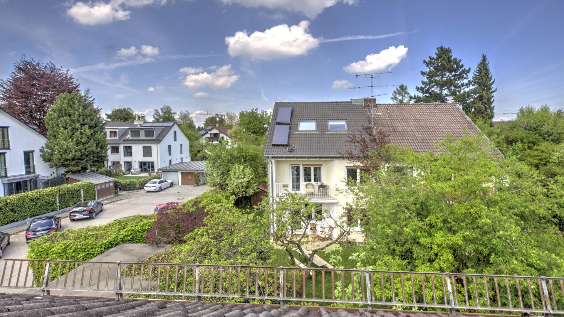 Blick von einem Balkon über Nachbarhäuser und Bäume im Stadtteil Bogenhausen in München
