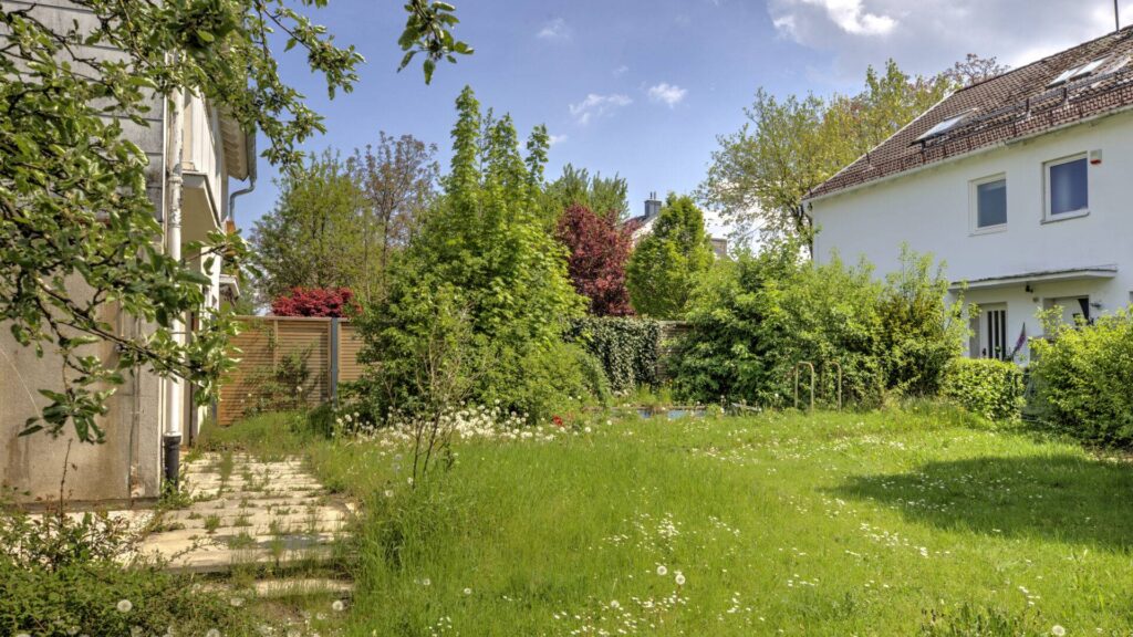 Well-kept garden with lawn area, path, and view of neighboring house at a house in Munich-Bogenhausen