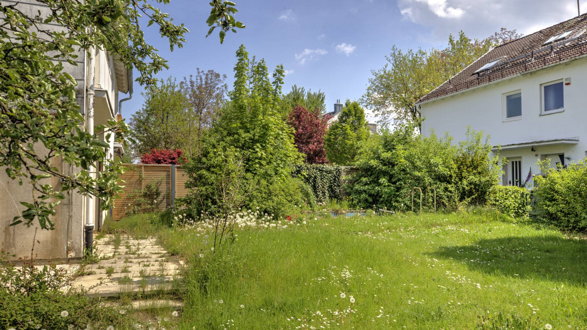 Gepflegter Garten mit Rasenfläche, Weg und Blick auf Nachbarhaus bei einem Haus in München-Bogenhausen