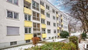 Facade with yellow balconies and entrance of a residential building in winter in Munich-Bogenhausen
