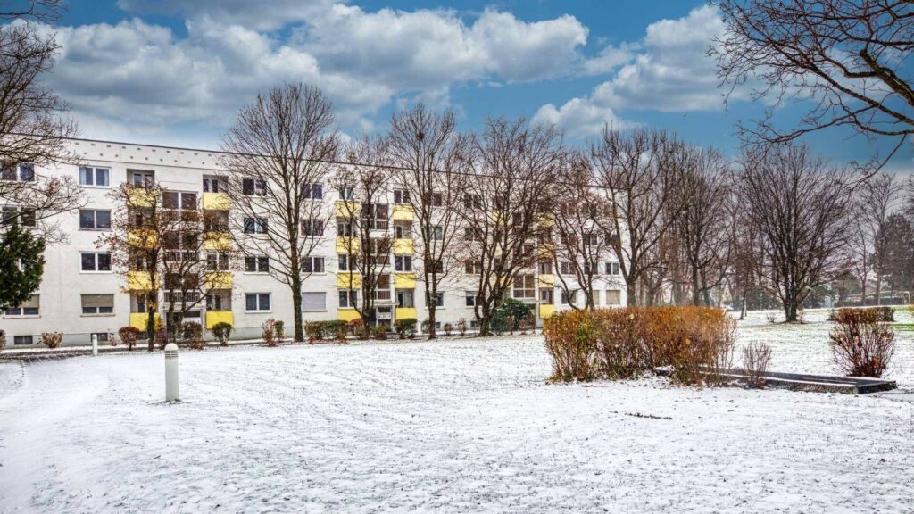 Multistory residential building with yellow balconies and snow-covered lawn in Munich-Bogenhausen