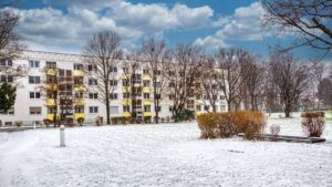 Multistory residential building with yellow balconies and snow-covered lawn in Munich-Bogenhausen
