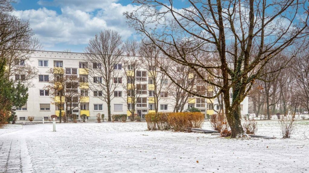 Multistory residential building with yellow balconies and snowy green space in Munich-Bogenhausen