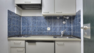 Small unrenovated kitchen with blue tiles and white cabinets in an apartment in Munich-Bogenhausen