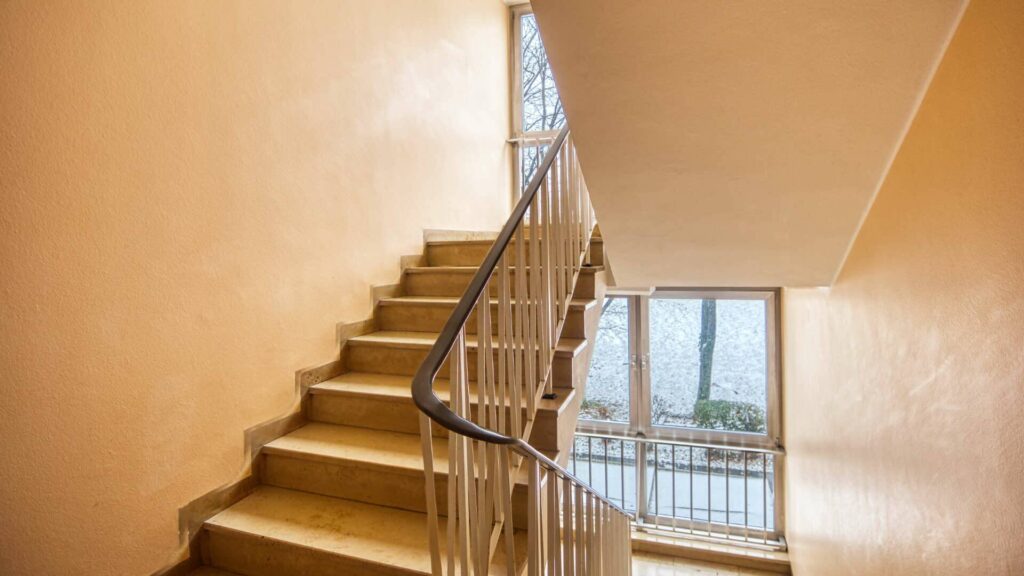 Cast-iron staircase with curved balustrades and large window in a residential building in Munich-Bogenhausen