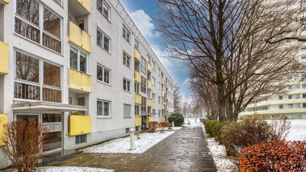 White house facade with yellow balconies and a snow-covered sidewalk in Munich-Bogenhausen