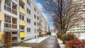 White house facade with yellow balconies and a snow-covered sidewalk in Munich-Bogenhausen
