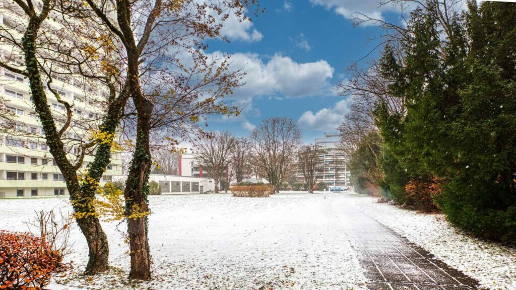 Snowy path between residential buildings with trees and hedges in Munich-Bogenhausen