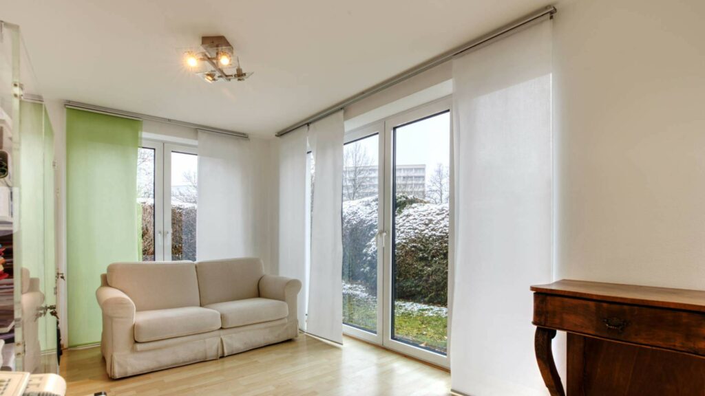 Aufenthaltsraum mit beigefarbenem Sofa, antiker Kommode und großen Fenstern im Büro in München-Forstenried