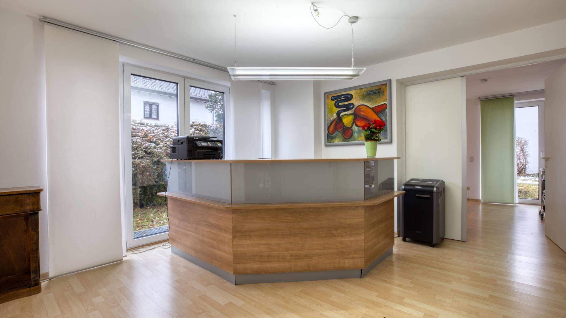 Reception desk made of wood and glass with a colorful wall mural in the office entrance in Munich-Forstenried