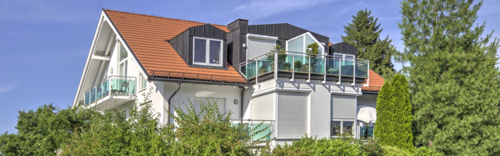 White apartment building with rooftop terrace and glass railing in the Forstenried district of Munich