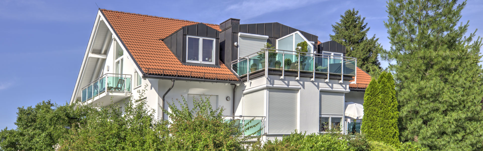 Weißes Mehrfamilienhaus mit Dachterrasse und Glasgeländer im Stadtteil Forstenried in München