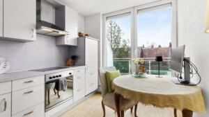 Weiße Küche mit rundem Esstisch und Balkontür in einer Wohnung in München-Forstenried