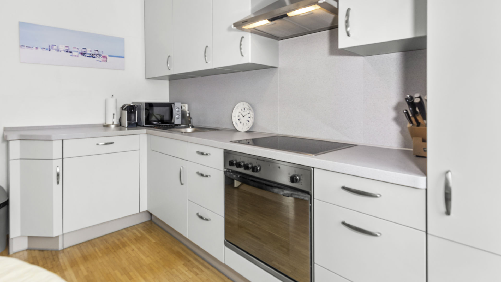 Weiße Einbauküche mit Herd, Dunstabzug und Anrichte in einer Wohnung in München-Forstenried