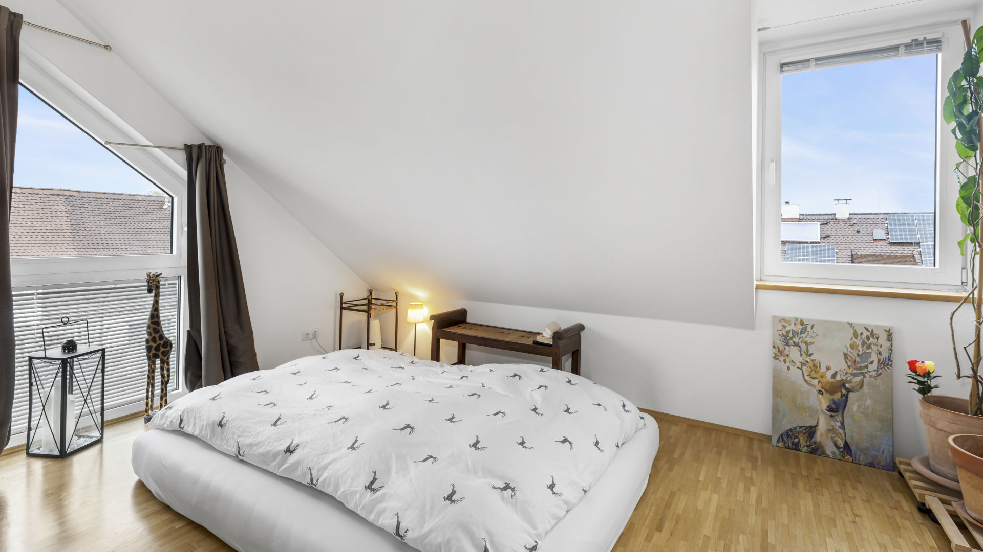 Schlafzimmer mit Bett unter der Dachschräge und Balkonzugang in einer Wohnung in München-Forstenried