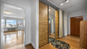 Hallway with built-in wardrobe in wood look and view into the living room in Germering – Rogers Immobilien