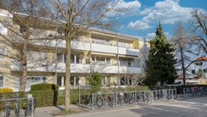 Apartment building with bicycle stands and a fence by the street in Germering – Rogers Immobilien