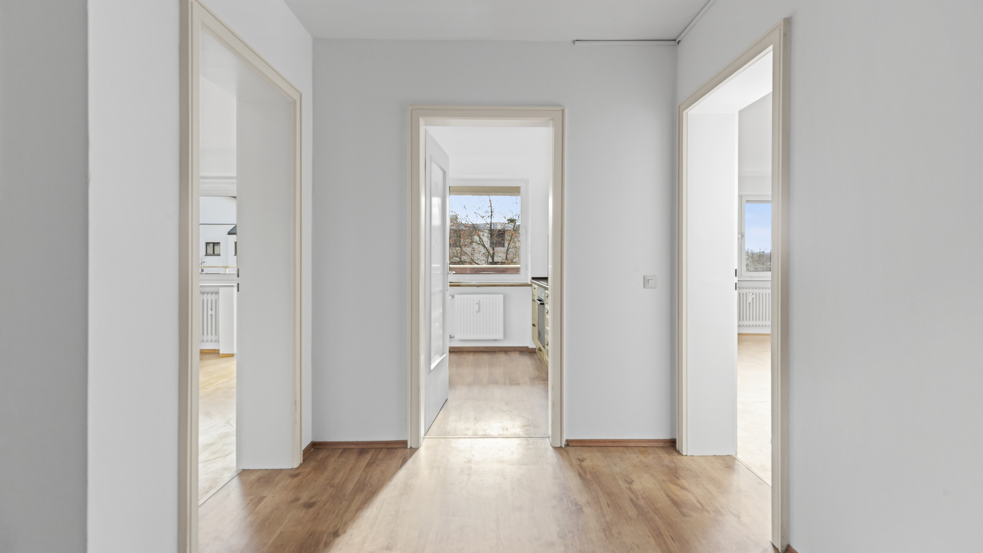 Diele mit hellem Parkettboden und Durchblick zu Küche und Schlafzimmer in einer Wohnung in Germering bei München