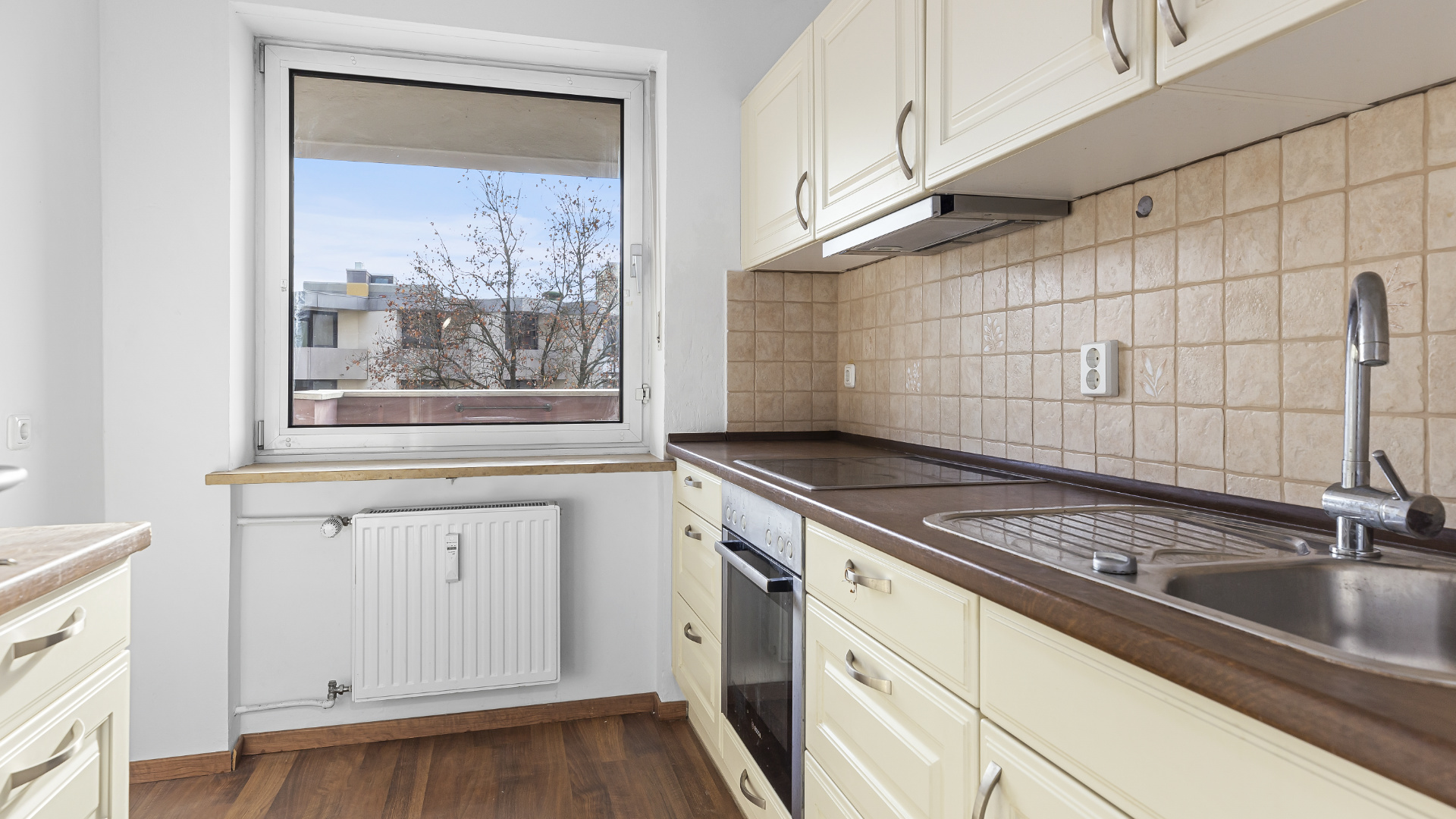 Ältere Einbauküche mit cremefarbenen Fronten und Fenster in einer Wohnung in Germering bei München