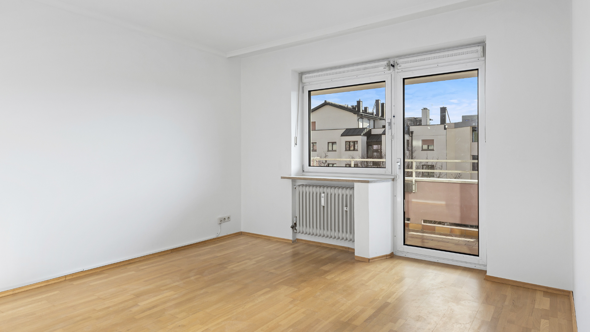 Unmöbliertes Schlafzimmer mit Parkettboden und Balkontür in einer Wohnung in Germering bei München