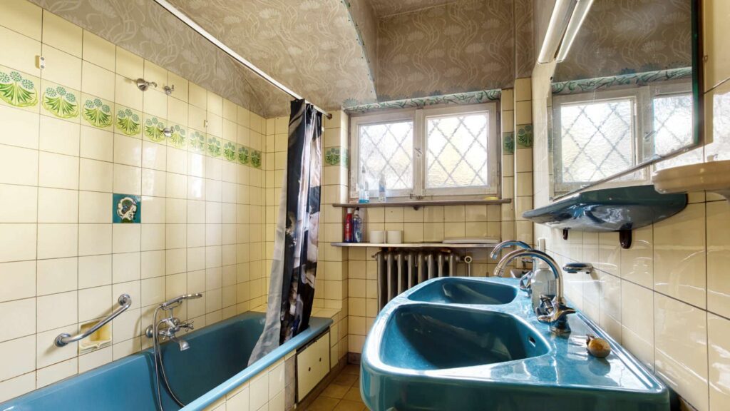 Unsaniertes Badezimmer im Erdgeschoss des Einfamilienhauses in München-Großhadern mit türkisfarbener Badewanne