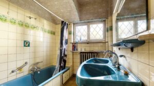 Unsaniertes Badezimmer im Erdgeschoss des Einfamilienhauses in München-Großhadern mit türkisfarbener Badewanne