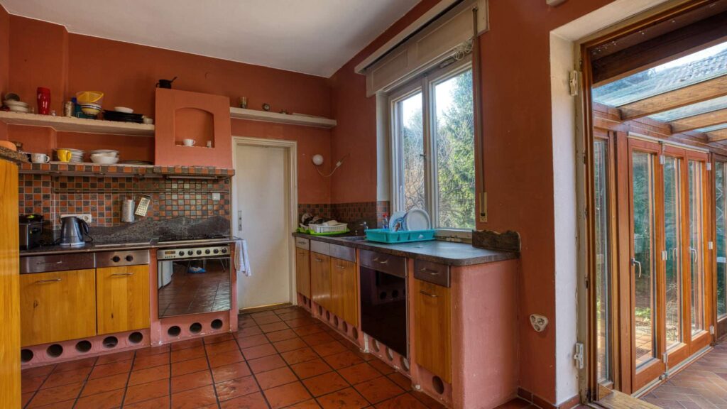 Küche im Erdgeschoss des Einfamilienhauses in München-Großhadern mit Terrakottafliesen und Wintergartenzugang