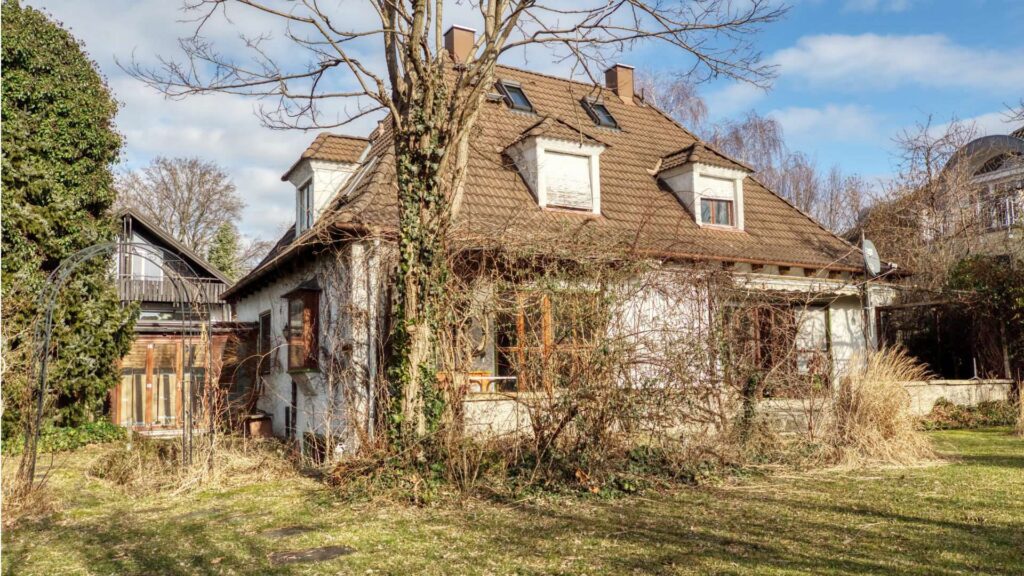 Rückansicht des unsanierten Einfamilienhauses in München-Großhadern mit Gauben und Garten