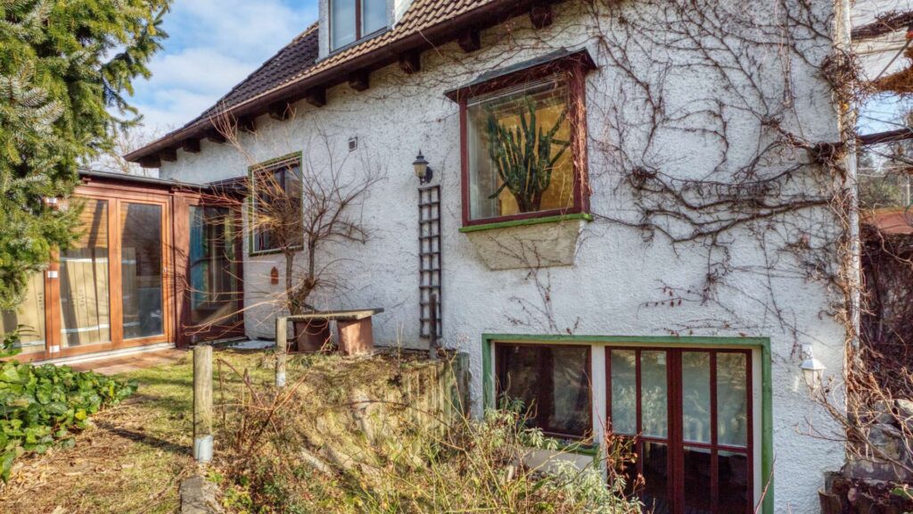 Hausansicht des Einfamilienhauses in München-Großhadern mit Wintergarten-Anbau und rankenden Pflanzen