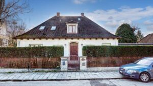 Straßenansicht des Einfamilienhauses in München-Großhadern mit Walmdach und winterlicher Straße