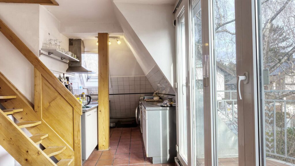 Küche im Obergeschoss des Einfamilienhauses in München-Großhadern mit Holztreppe und Balkontür