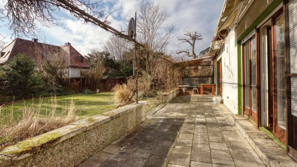 Terrasse des Einfamilienhauses in München-Großhadern mit gepflasterter Fläche und Garten
