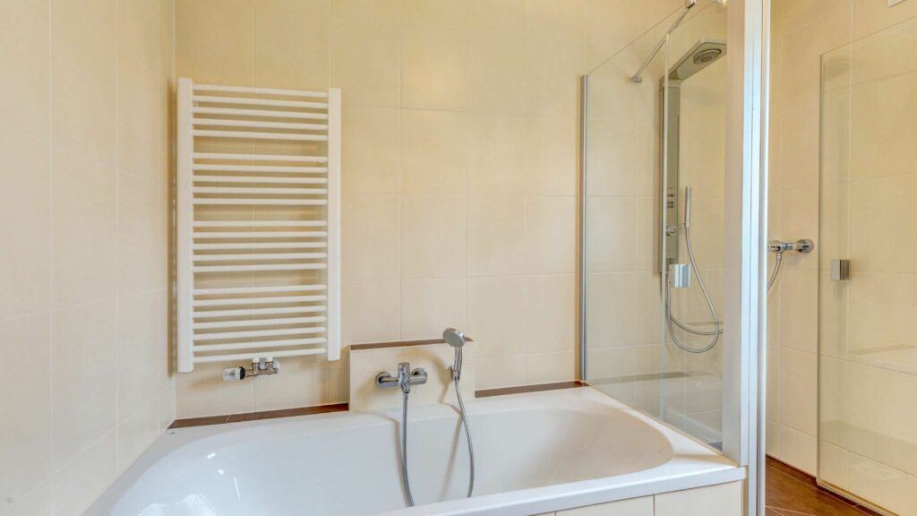 Bathroom of the apartment in Munich-Großhadern with bathtub and white towel heater