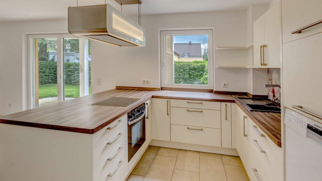 Kitchen installation in an apartment in Munich-Großhadern with cream-colored fronts and a wooden worktop