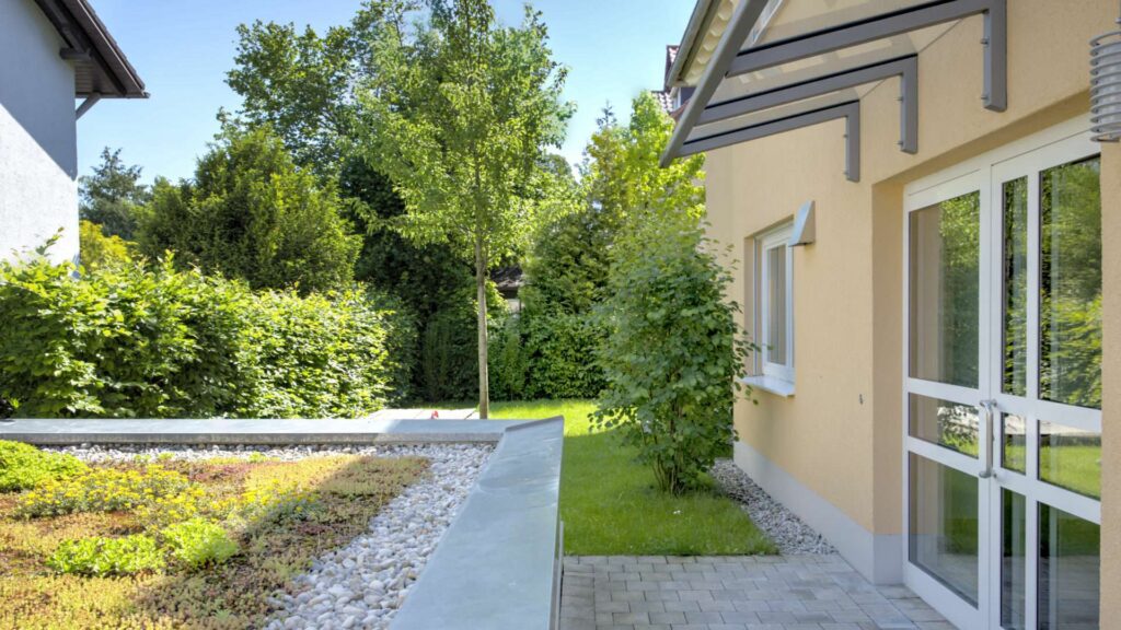 Entrance area of the apartment in Munich-Großhadern with a yellow facade and paved path