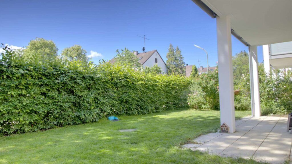 Garden area of the apartment in Munich-Großhadern with high hedge and covered terrace