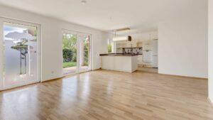 Empty living area of the apartment in Munich-Großhadern with a view of the open kitchen