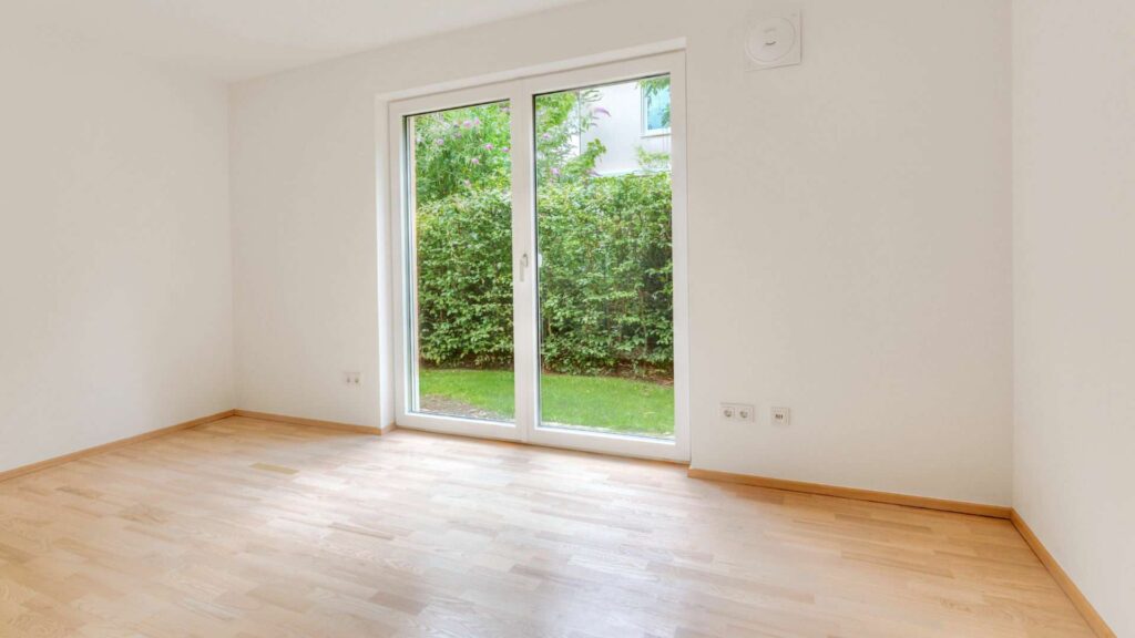 Empty room in the apartment in Munich-Großhadern with a patio door and parquet floor