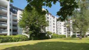 Mehrstöckiges Wohngebäude mit Rasenfläche, Bäumen und Balkonen in München-Hadern