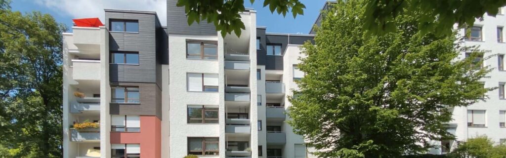 Fassade eines mehrstöckigen Wohngebäudes mit Balkonen und Bäumen in München-Hadern