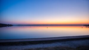 Calm water surface of the Ammersee with sky gradient near Herrsching