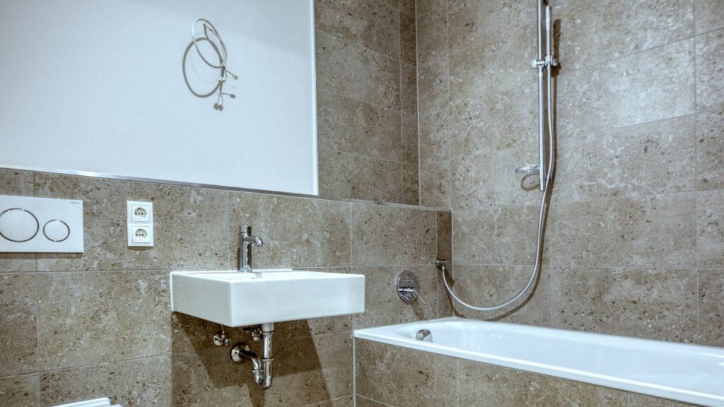Detail view of washbasin, mirror and bathtub with stone tiles in an apartment in Herrsching