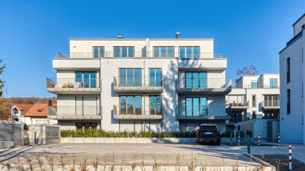 White facade with large windows and balconies of a new building on the street in Herrsching