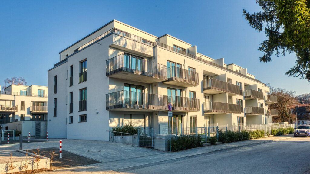 Modern white facade with large windows and balconies of a new building in Herrsching