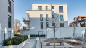 Modern courtyard with benches and trees between new buildings in Herrsching