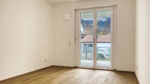 Unfurnished bedroom with parquet flooring and balcony door in a newly built apartment in Herrsching