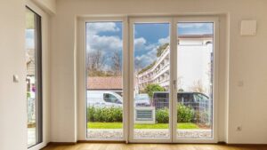 Empty living room with a three-piece window front and parquet flooring in a new apartment in Herrsching