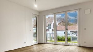 Unfurnished living room with parquet flooring and large patio door in a newly built apartment in Herrsching